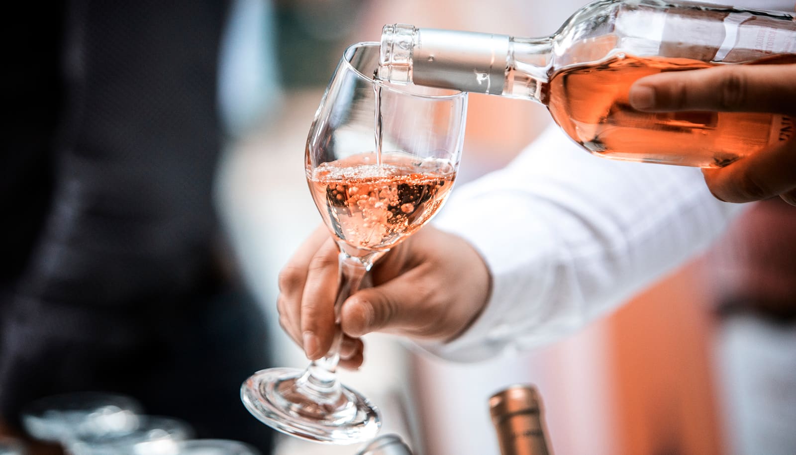 Sparkling rose wine being poured into a glass - decanting a wine