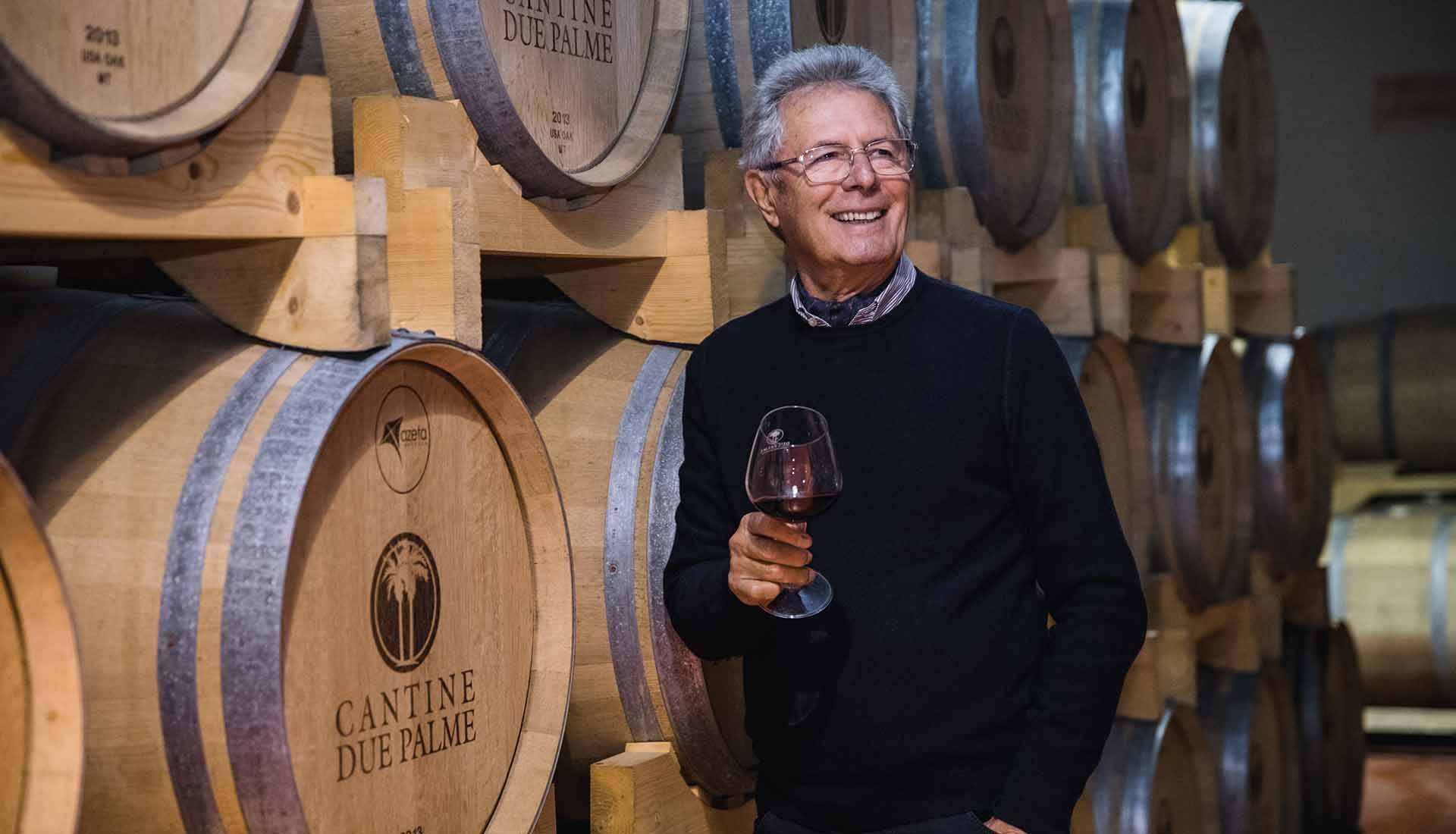 Winemaker Angelo Maci stands in his winery next to wine filled oak barrels