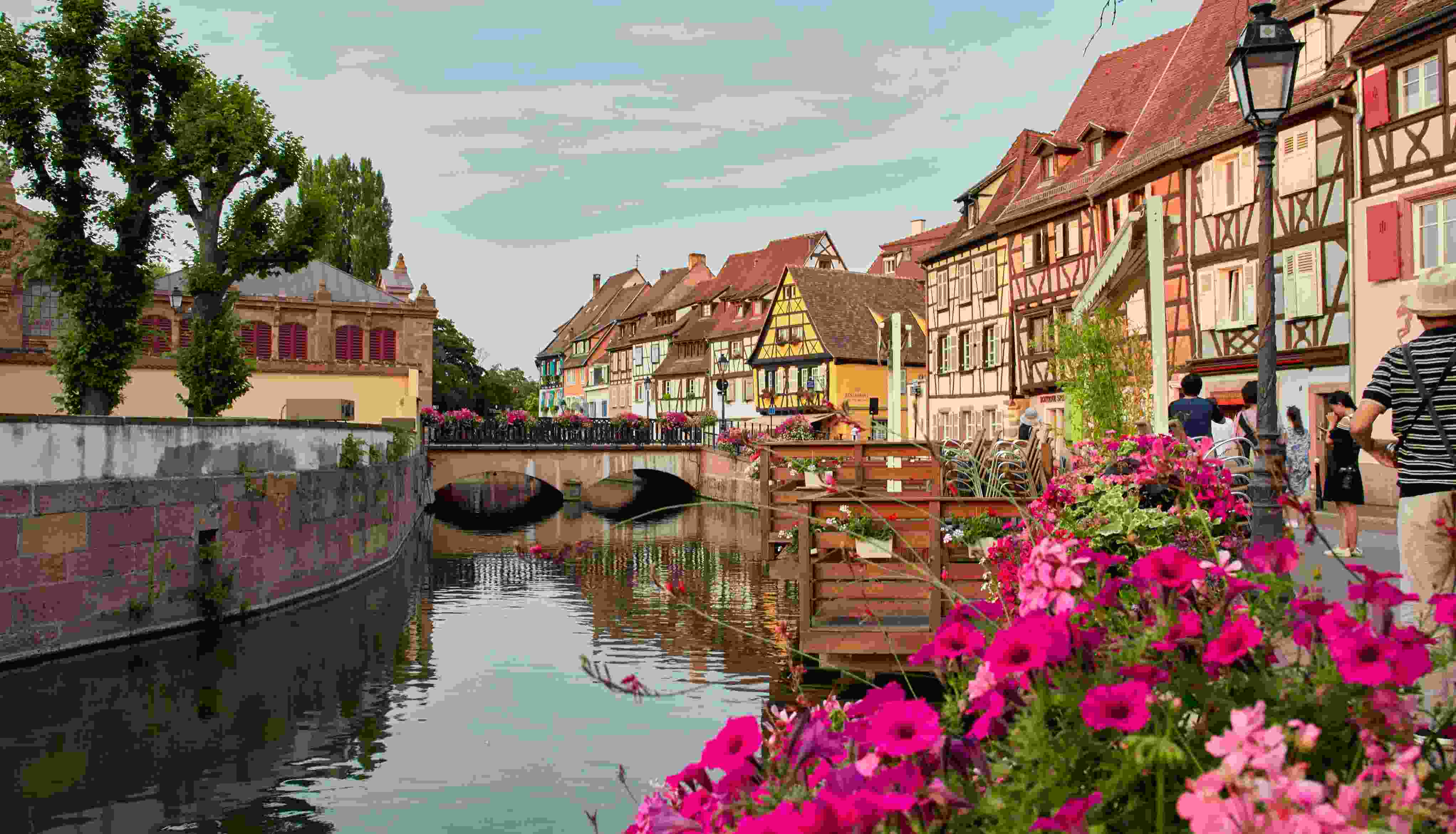 A canal in Alsace with picturesque timbered buildings and flowers in the foreground