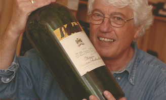 Man in denim shirt with white hair holding double magnum wine bottle