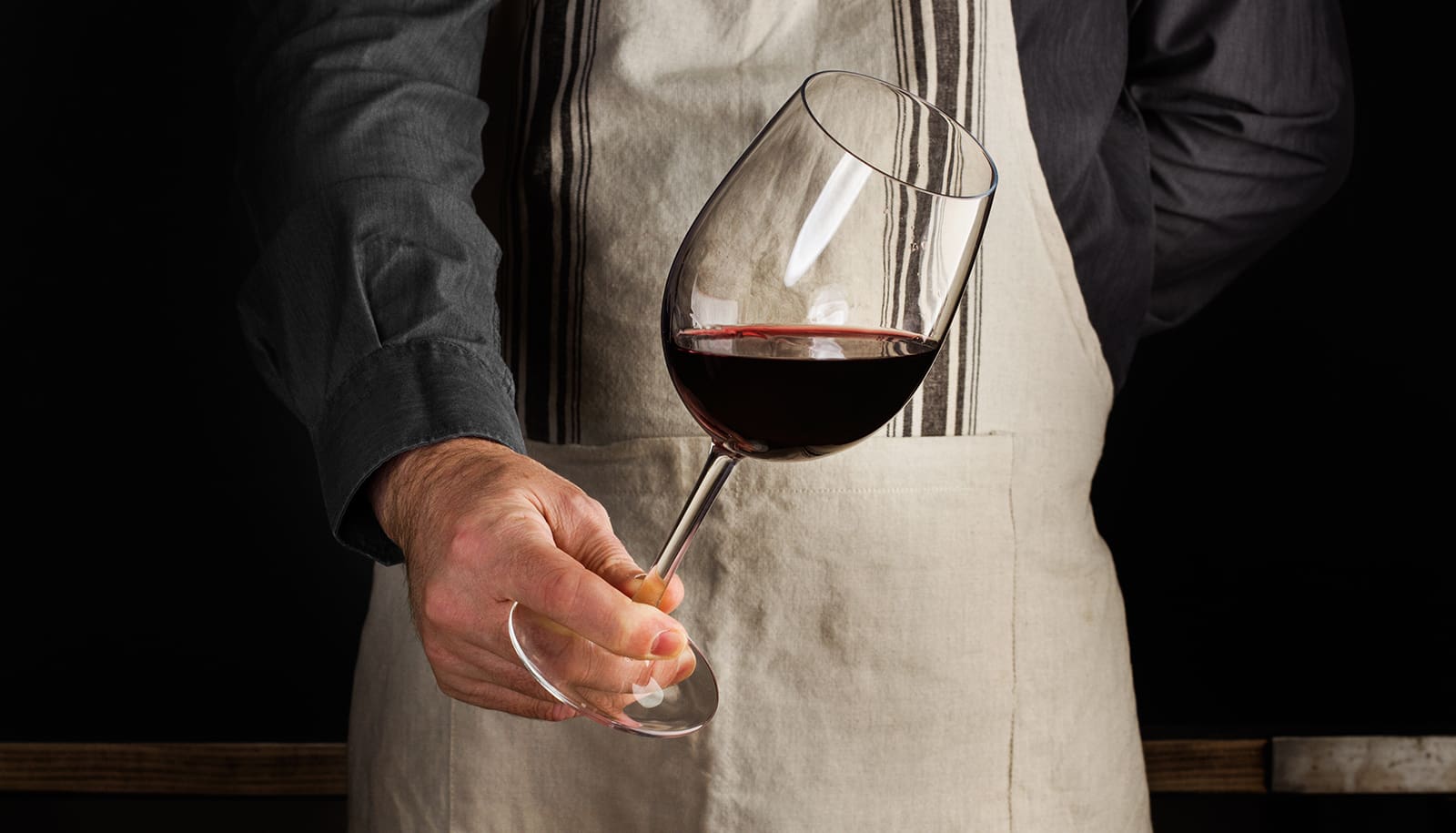 A sommelier holding a glass of wine and inspecting the colour - decanting a wine
