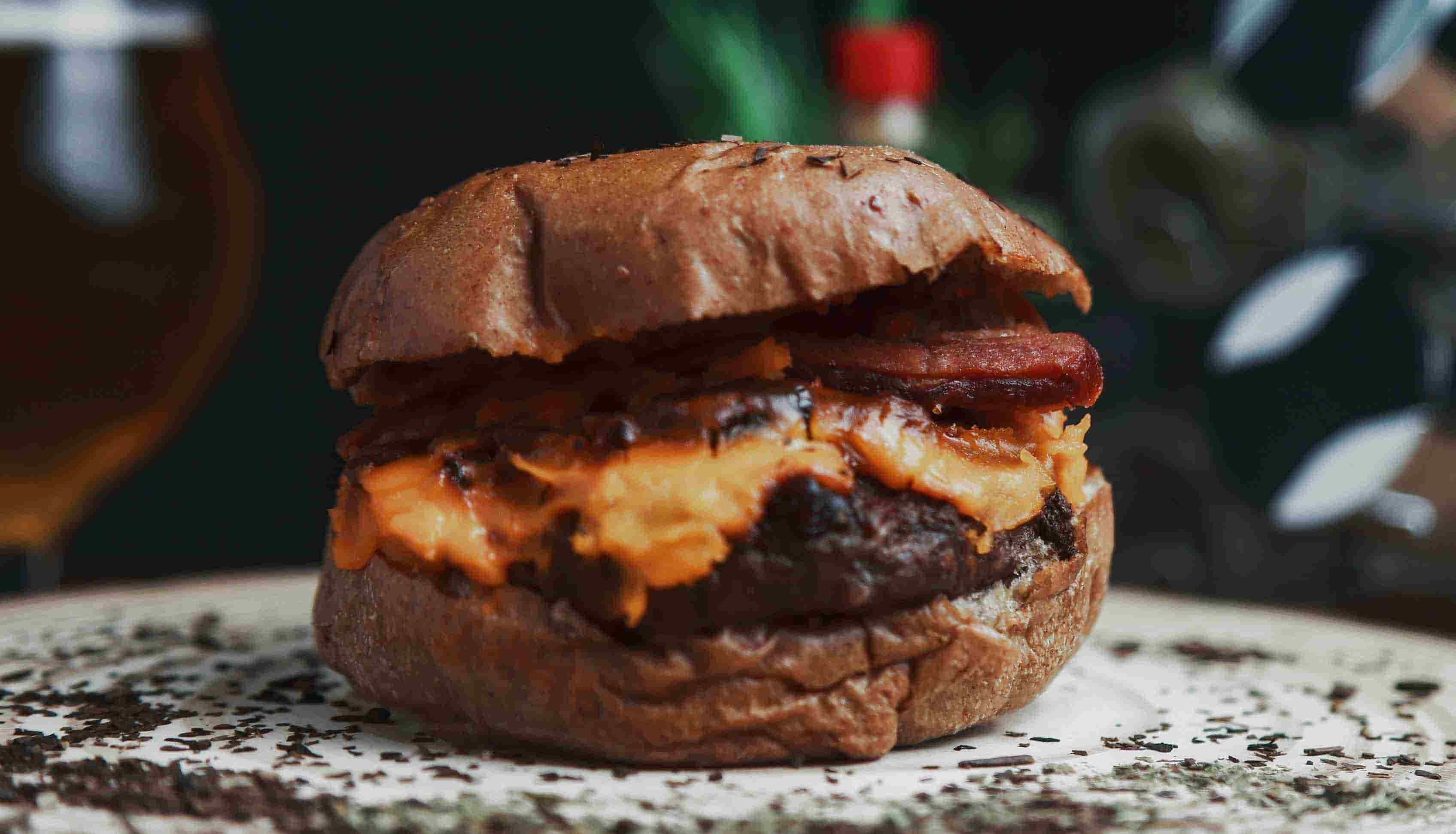 An image of a beefburger with bacon and cheese