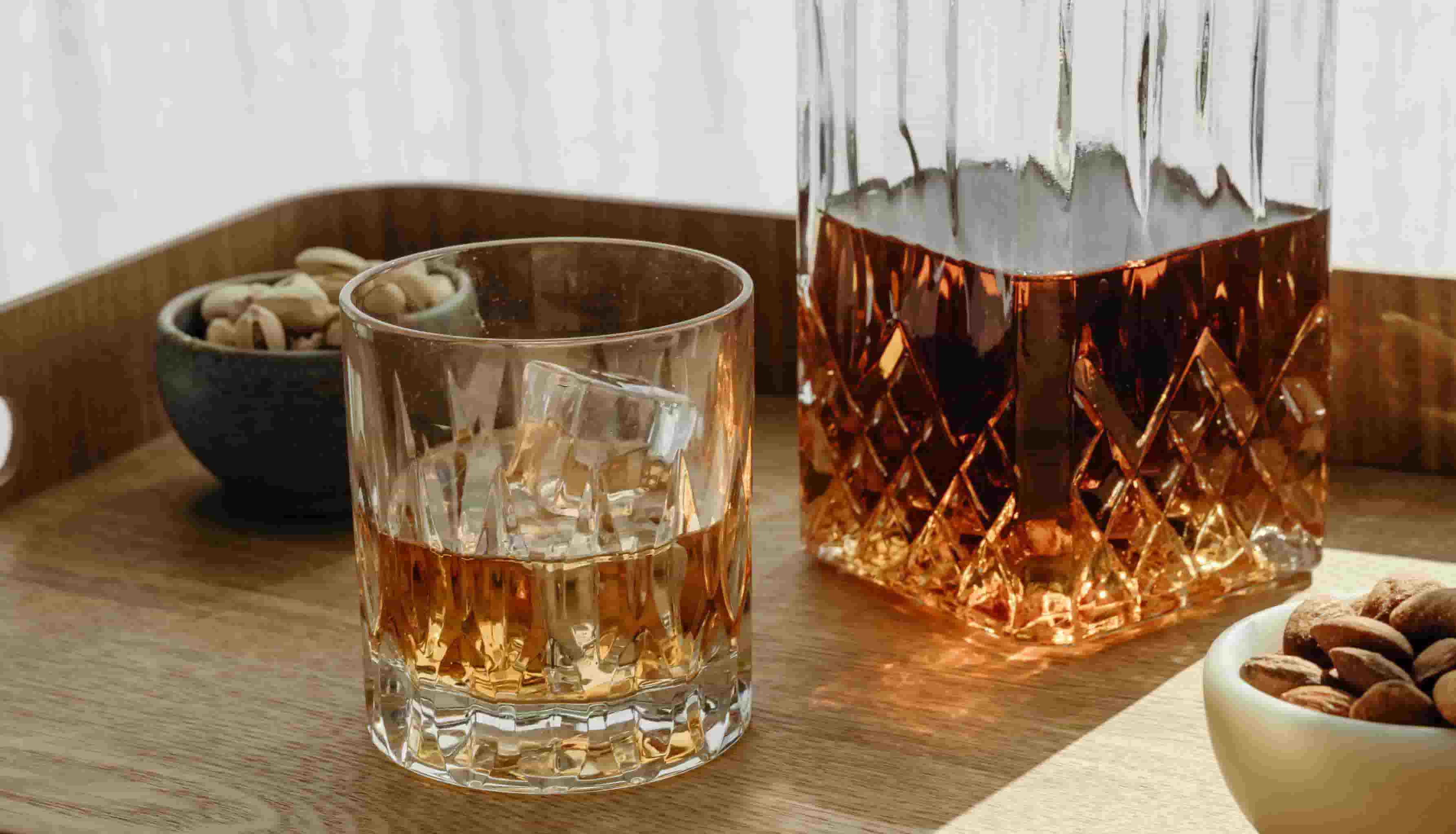 A glass of whiskey on a table with a decanter next to it