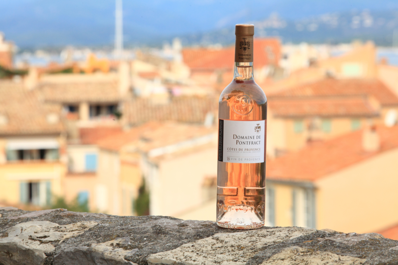 Bottle of Domaine Pontfract rose on a stone wall overlooking Provence