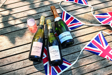 3 bottles of Wyfold Brut Rosé. Wyfold Brut and Harrow and Hope Brut on a wooden deck with Union Jack bunting to celebrate the coronation