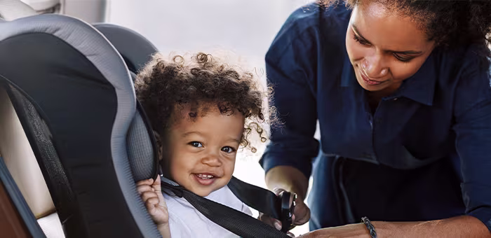 Mamá con su pequeño poniéndole silla para bebé de auto.