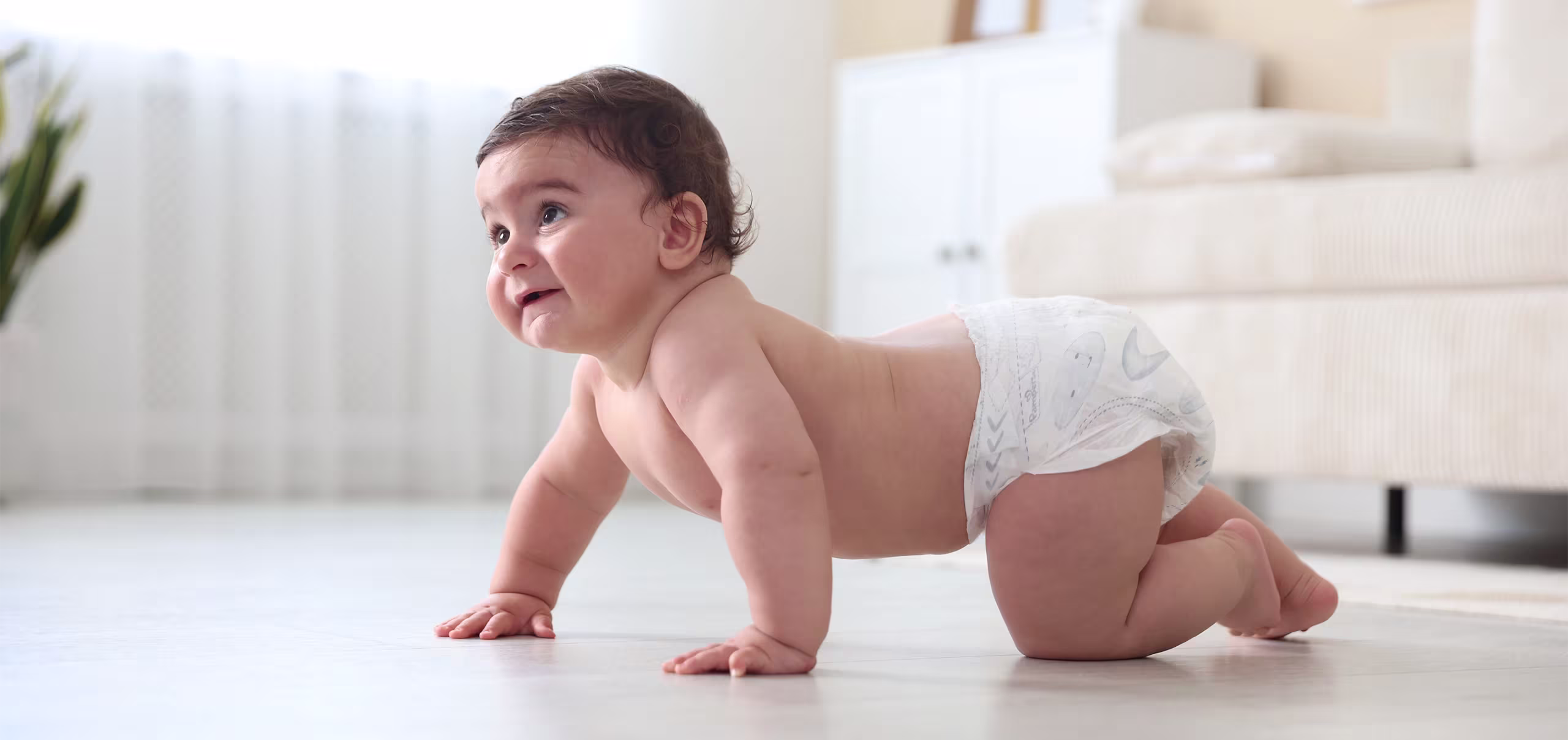 Bebê engatinhando confortavelmente com fralda Pampers em ambiente acolhedor.