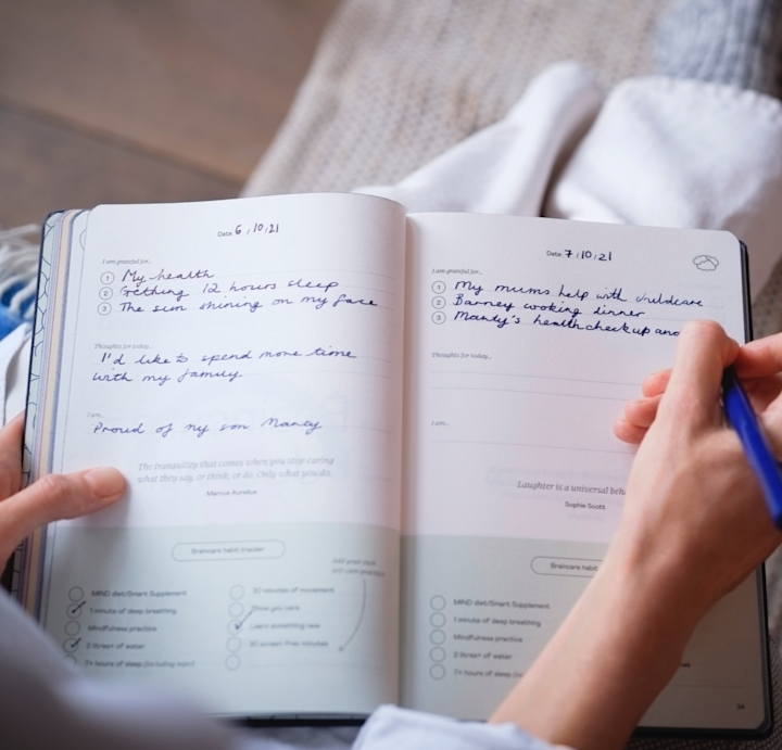Braincare Journal with someone writing a journal entry