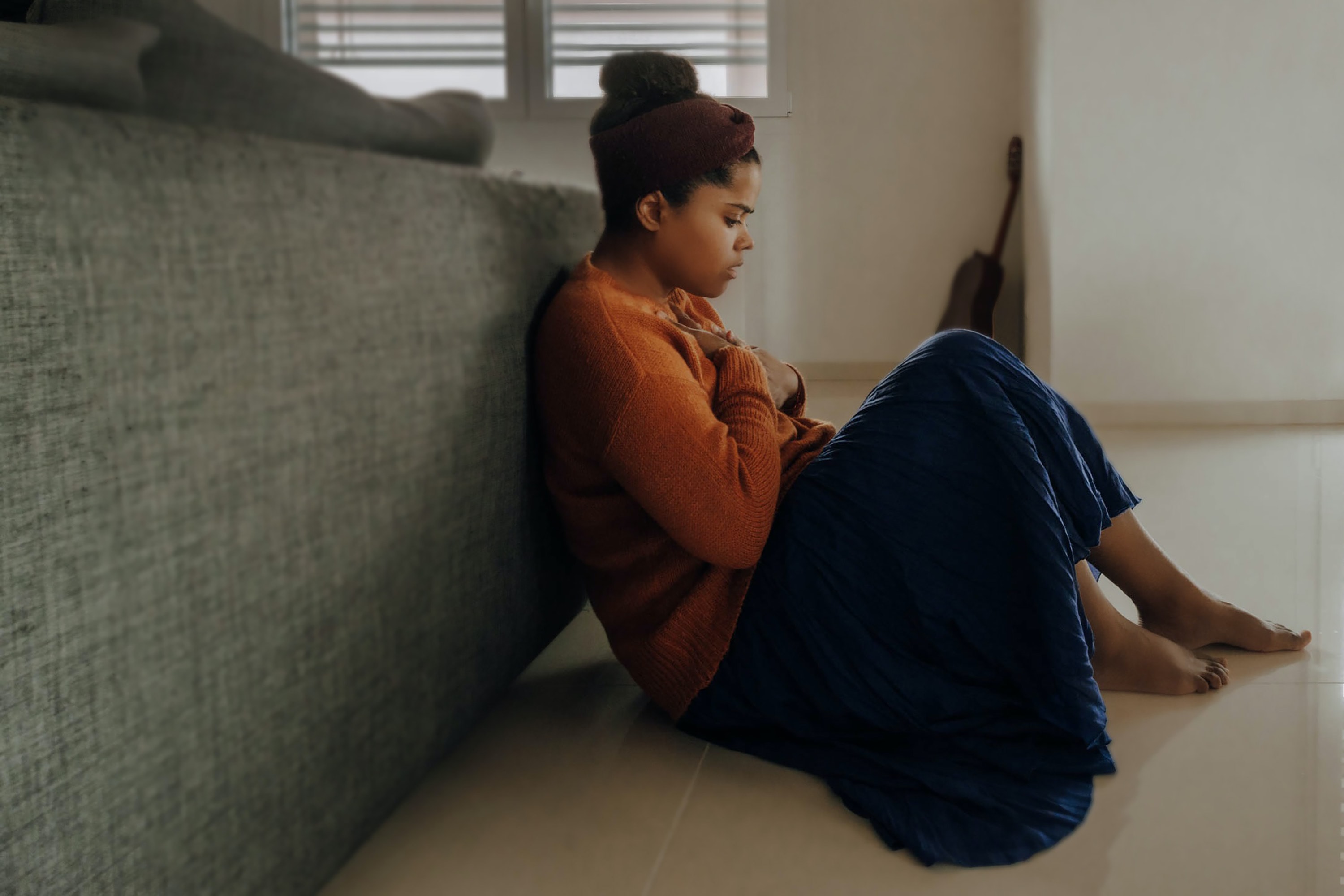 Women sitting sad leaning against a bed