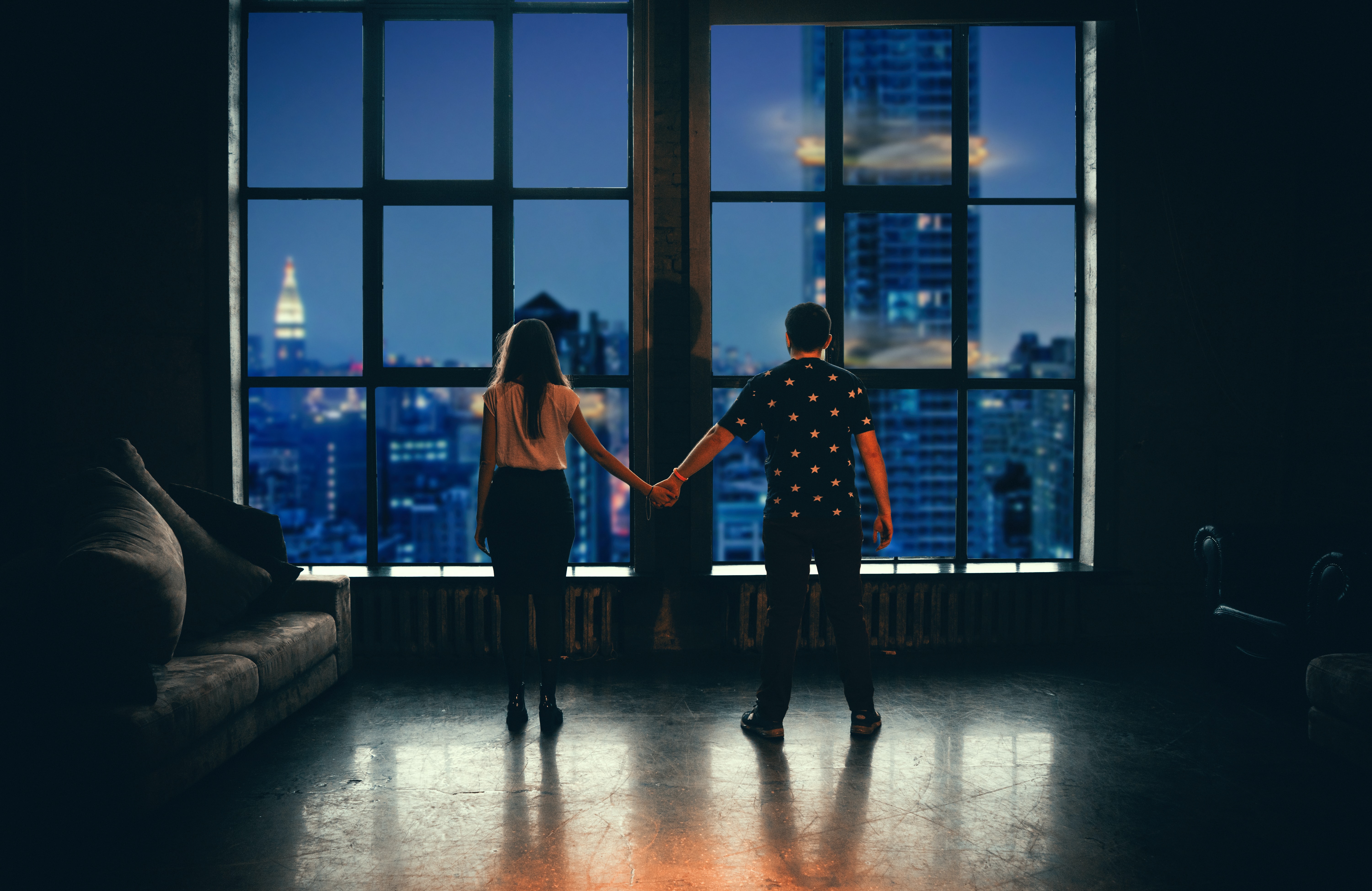 Two people holding hands in front of a large window