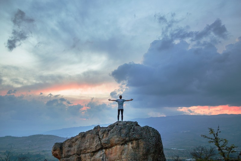 Man standing on a mountain in front of a cloudy sky