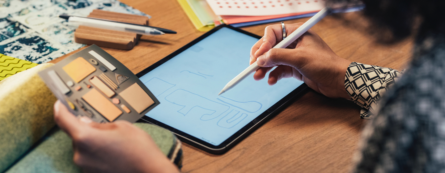 Designer sketching on tablet while looking at reference image