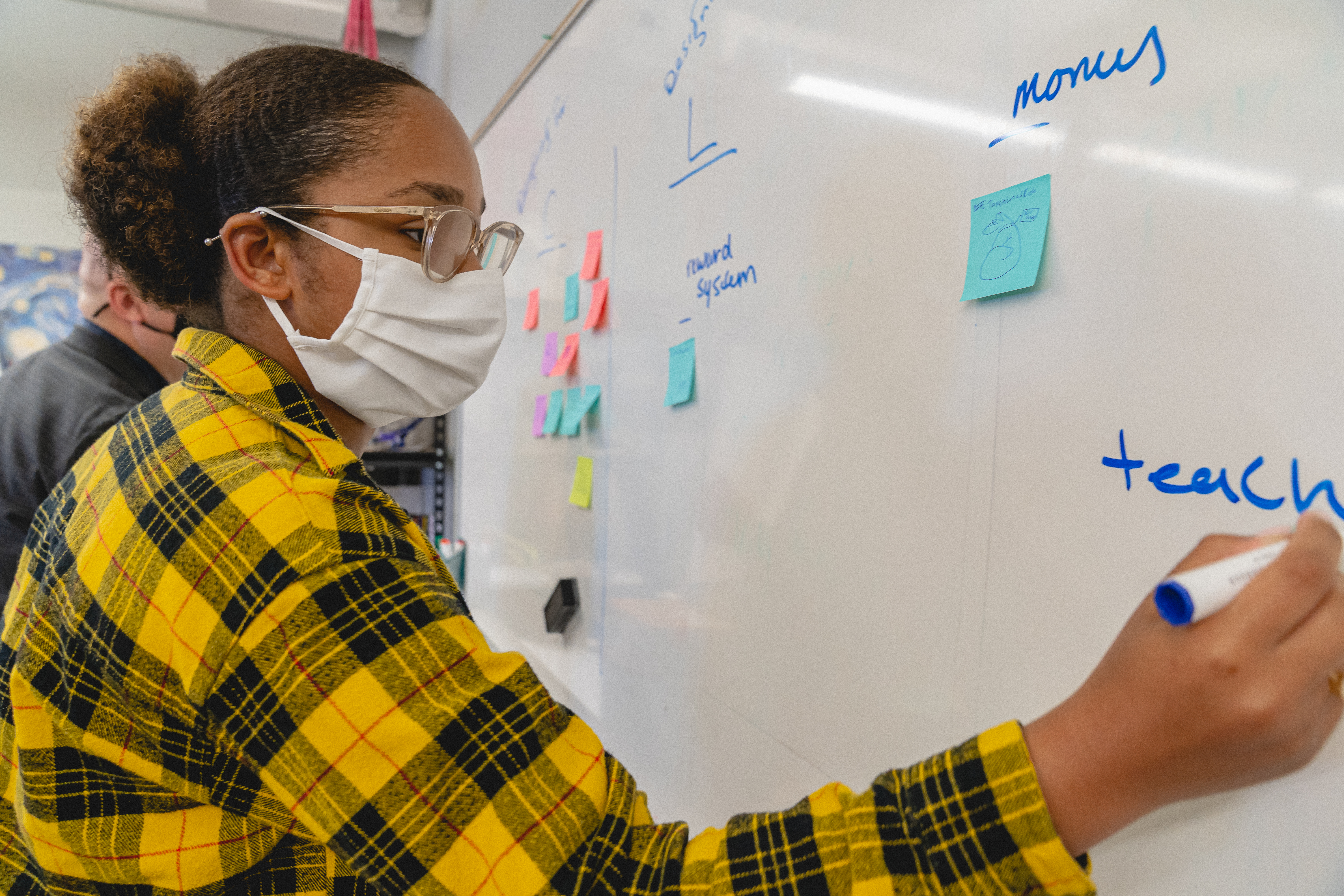 A student writes ideas on a whiteboard.