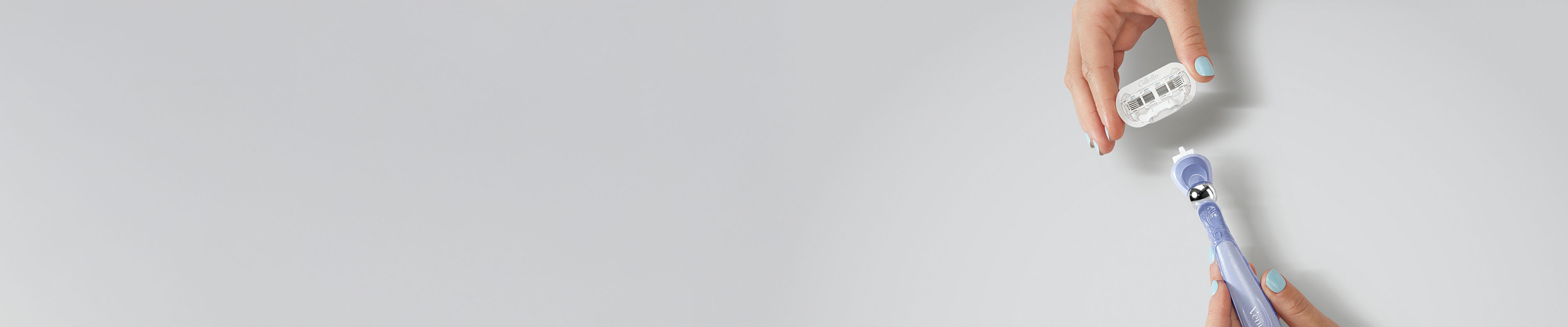 A feminine hand with polished nails mounting a razor blade refill on the Gillette Venus handle