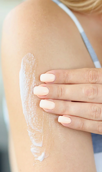 Moisturizer is applied to an arm by female hands