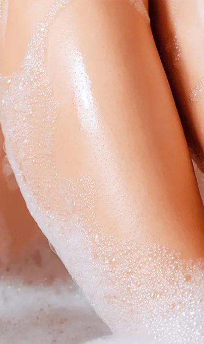 Ein Bein in der Badewanne, bedeckt mit Seifenschaum