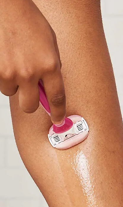 Eine Person rasiert ihr Bein mit einem Gillette Venus Rasierer und zeigt glatte Haut und Rasiergel auf der Oberfläche.