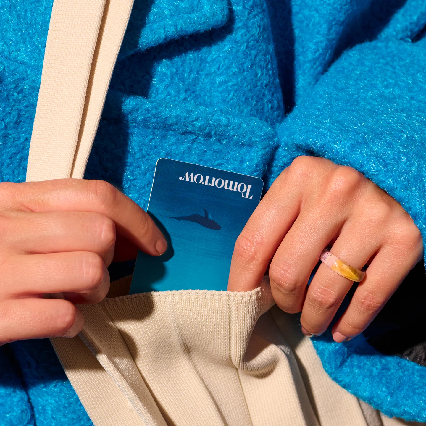 Hand putting a blue Tomorrow card into a bag - stage image for the Girokonto page
