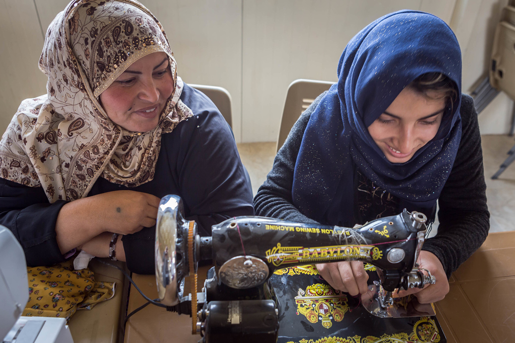 Two women working together at the sewing machine.