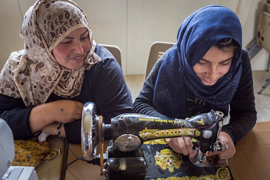 Two women working together at the sewing machine.