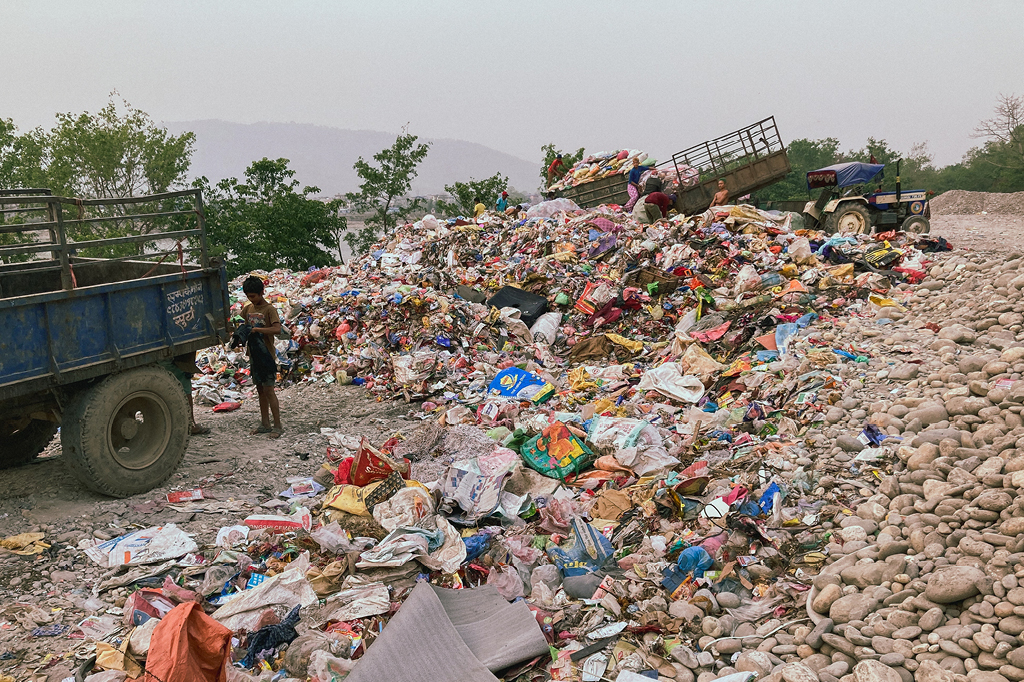 Ein Kind vor einem großen Berg an Plastik, das bald recycled wird.