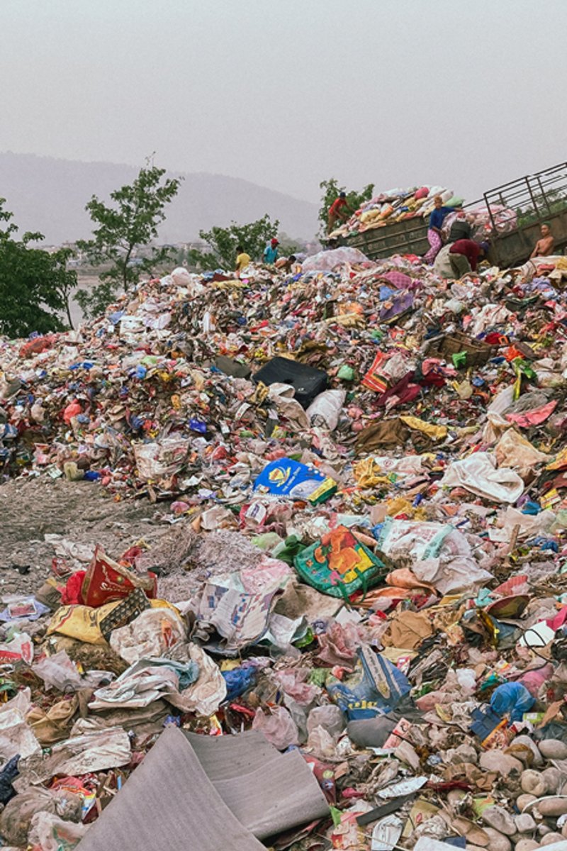 Ein Kind vor einem großen Berg an Plastik, das bald recycled wird.