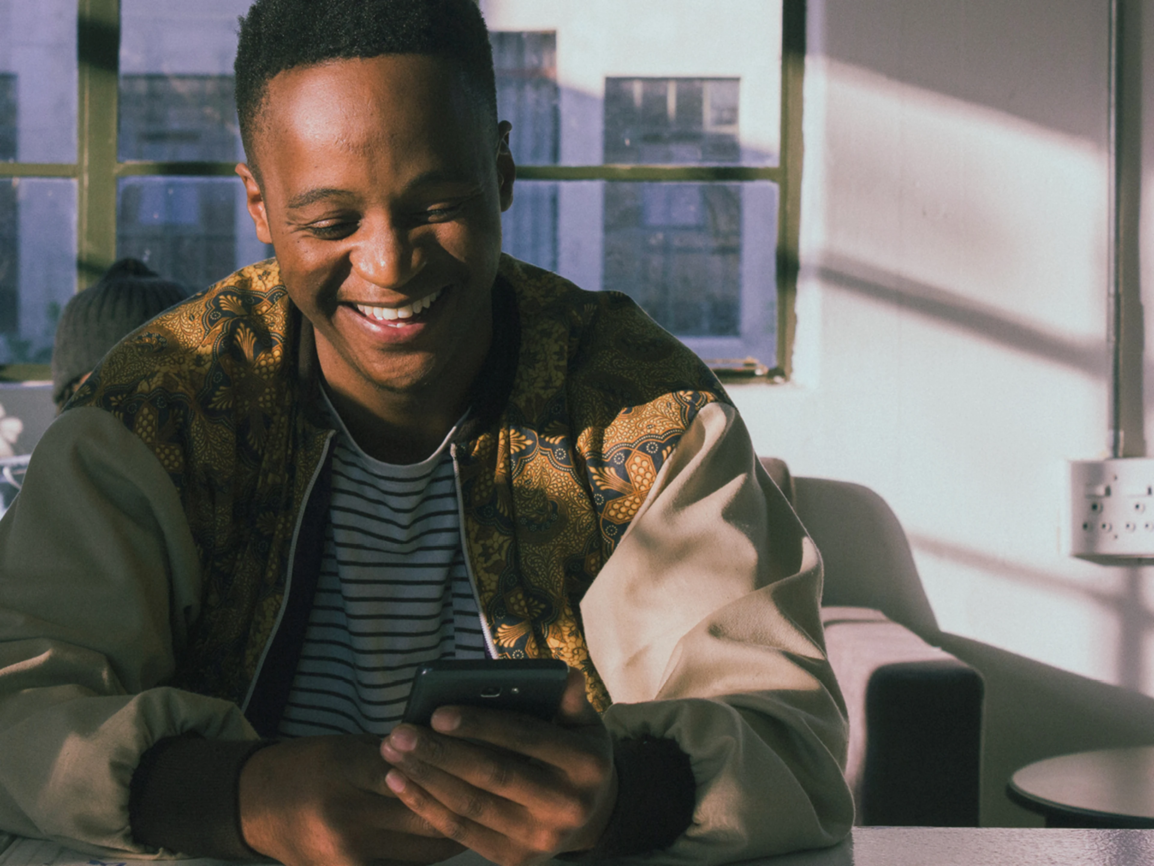 A young man is looking at his smartphone and is happy.