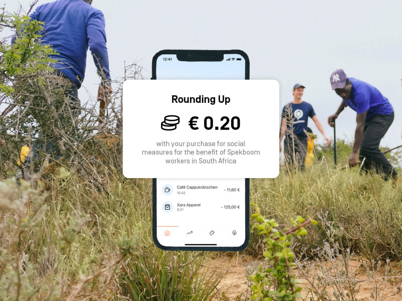 In the background is a picture where men are working on a field. In the front is a picture of the Rounding Up-Feature saying "Rounding Up 0,20 € with your purchase for social measures for the benefit of Spekboom workers in South Africa".