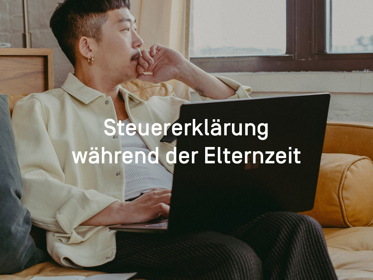 Person sitzt mit Laptop auf dem Schoß auf der Couch und schaut nachdenklich aus dem Fenster.