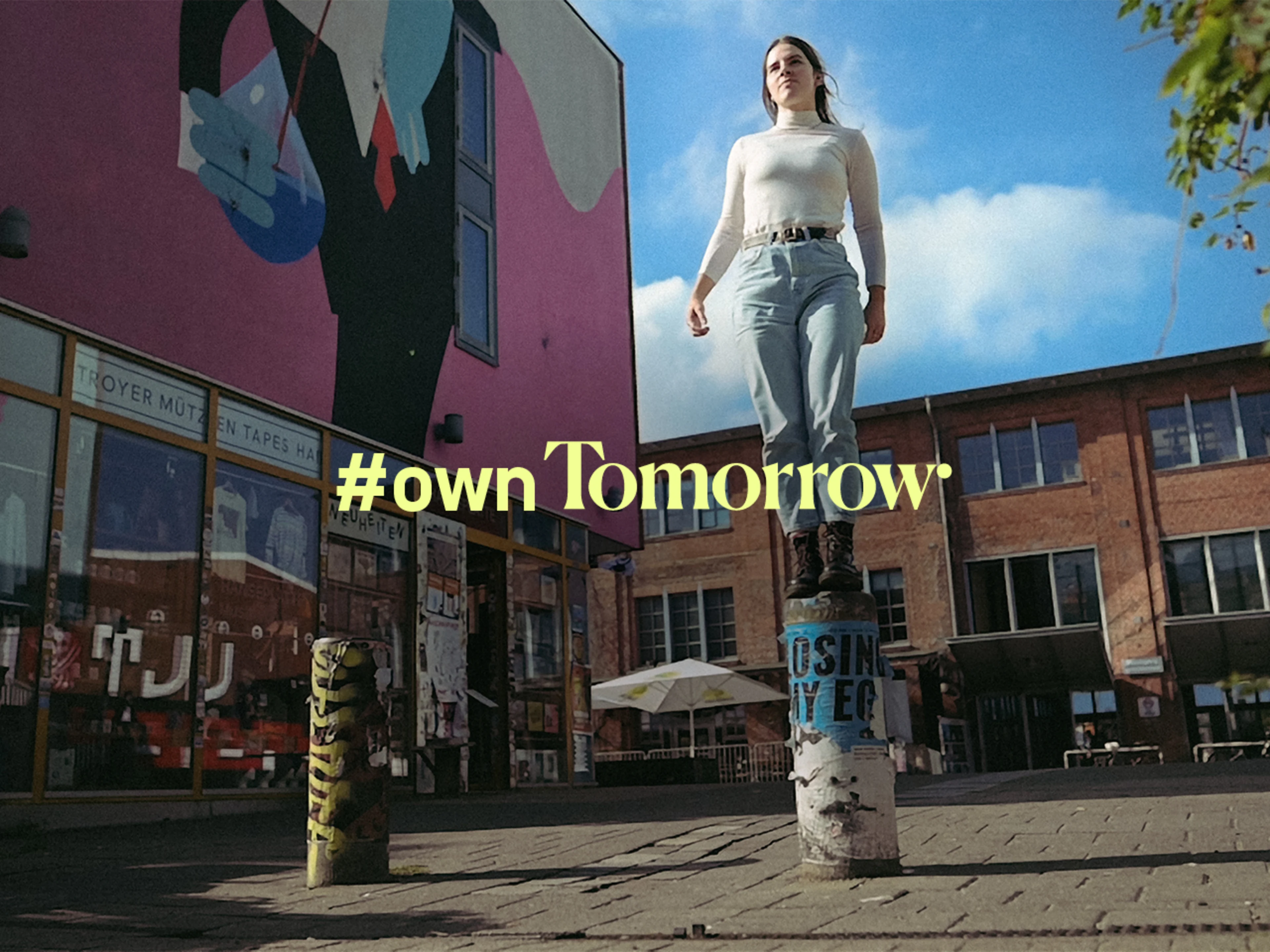 Frau steht auf einem Poller. Daraud die Schrift: #OwnTomorrow