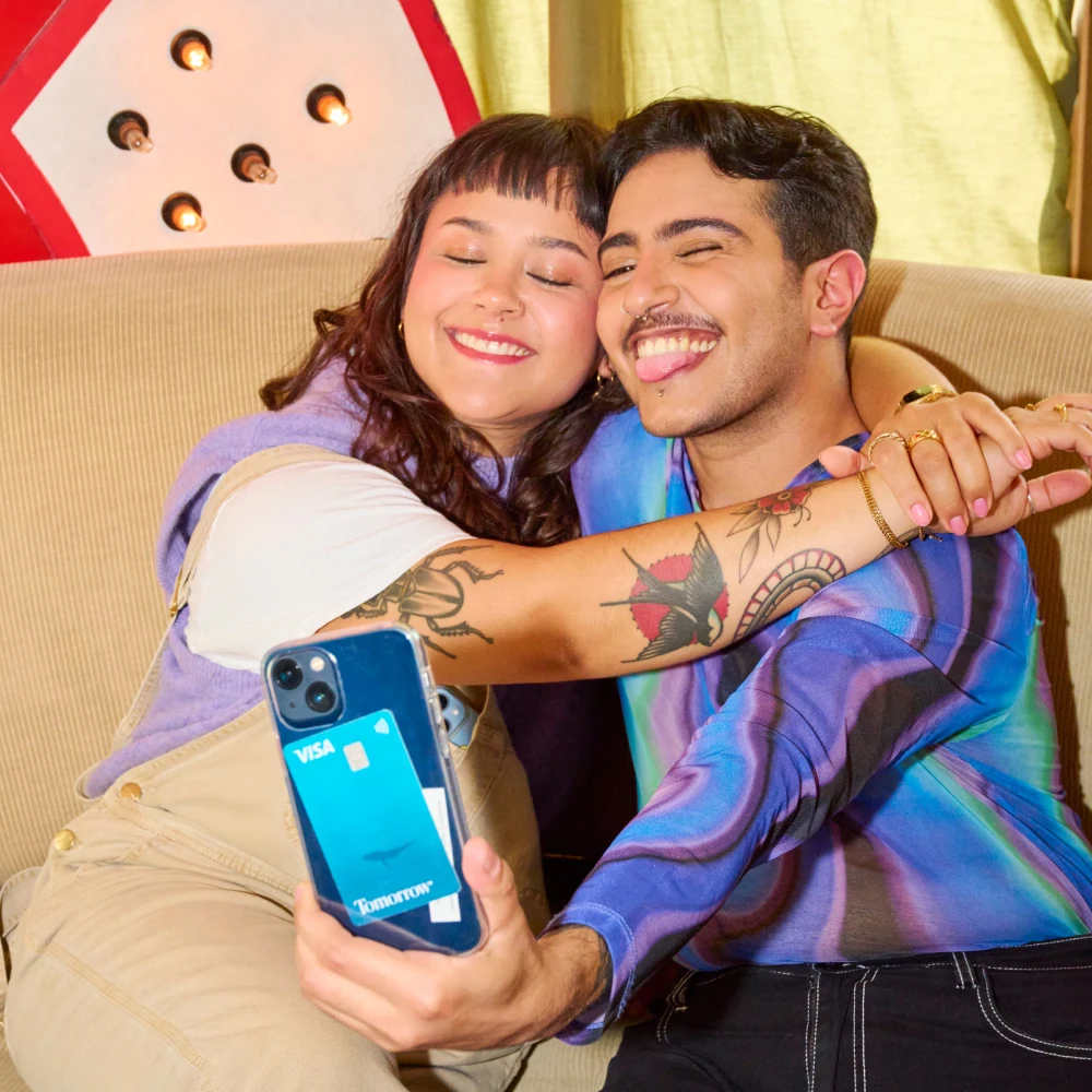 Two people hugging while taking a selfie. Tomorrow's card is in the transparent cover of the mobile phone.