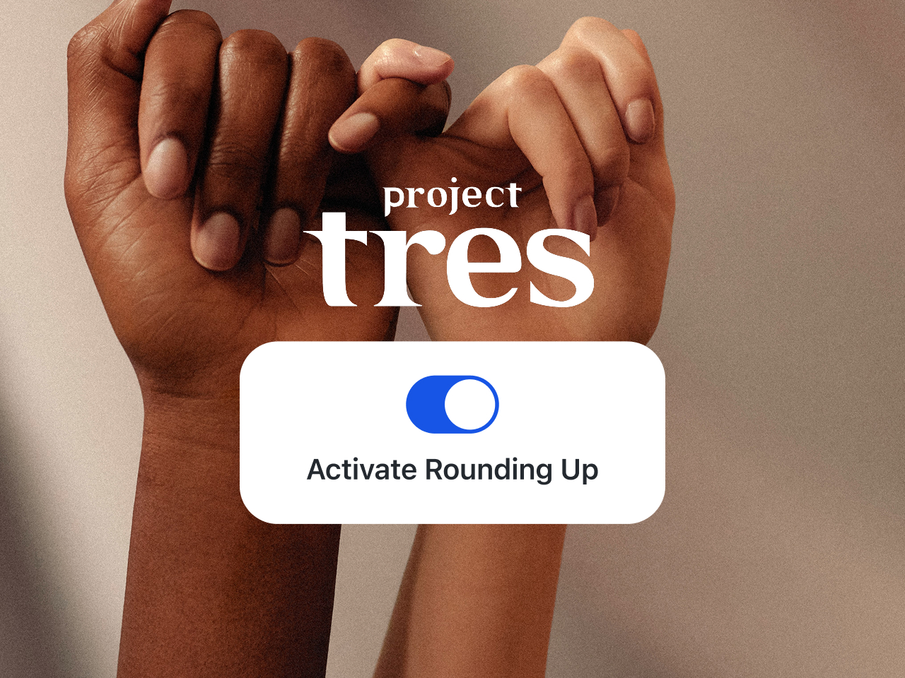 Two hands are intertwined, following the “pinky promise” gesture, with the little fingers wrapped around each other. The left hand belongs to a person of color, and the right hand belongs to a white person. The background is blurred, with natural light falling on a natural-colored wall. The image features the logo of the organization “Project Tres” and a pop-up window with a button to activate Rounding Up in the app. 