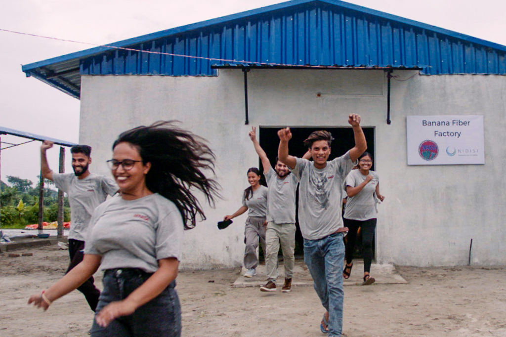 Zu sehen sind Mitarbeitende des Nidis-prjekts, die freudig aus einer Produktionsstätte laufen.