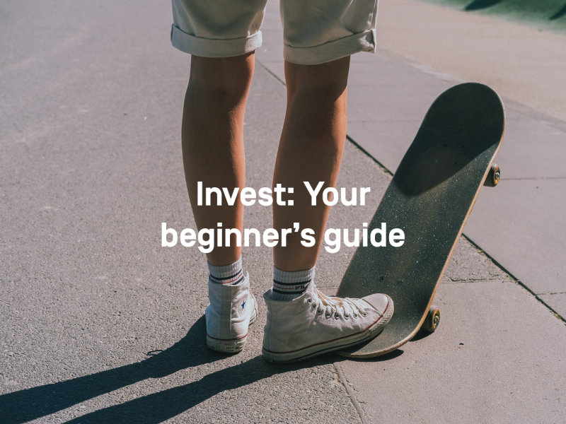A young man in shorts and Chucks stands on the street. His right foot is on the back of a skateboard, the front wheels are in the air. 
Text: Invest: Your beginner's Guide