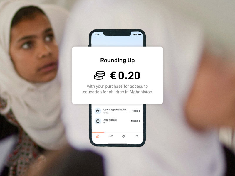 Photography of girls in a classroom with the app screen and text on it: Rounding Up: € 0.20 with your purchase for access to education for children in Afghanistan 