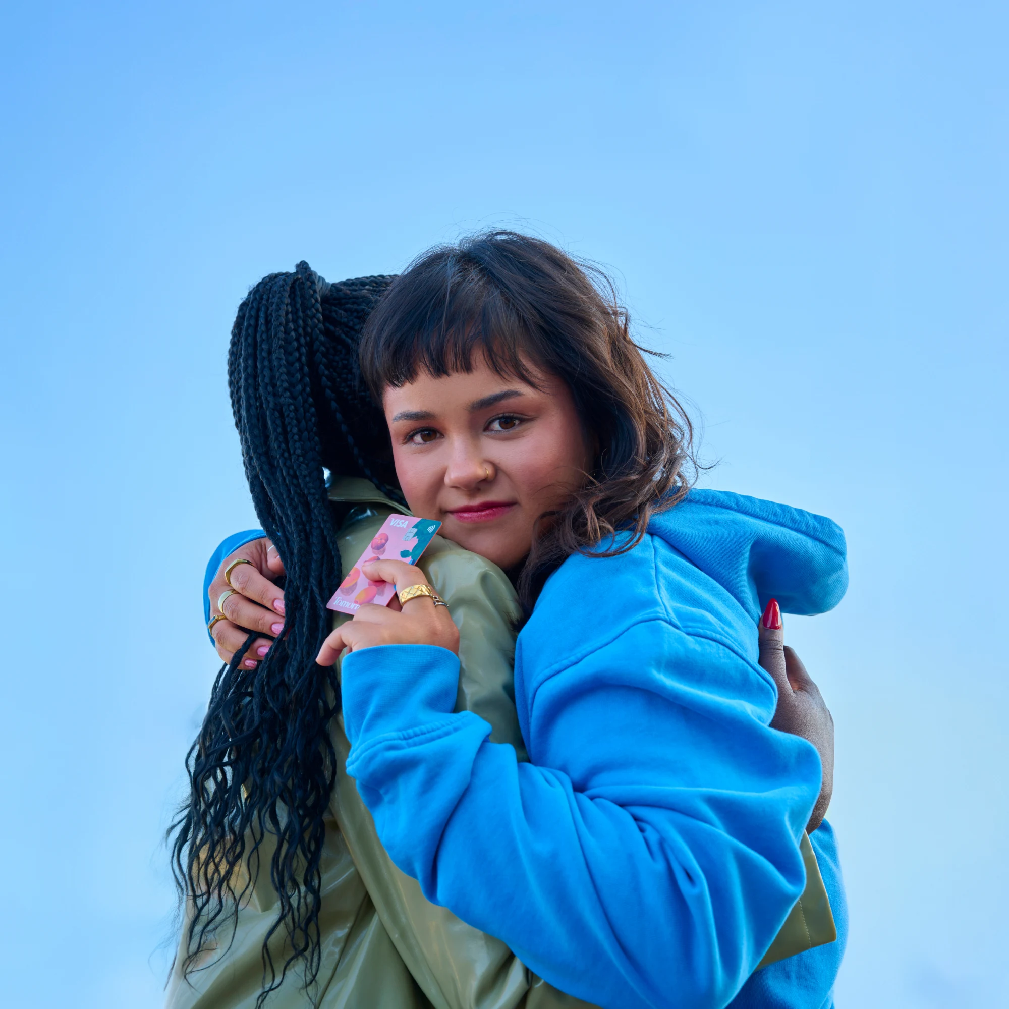 Two children of different ethnicities hugging each other, one of them holding Tomorrow's card and gazing intently as a sign of looking toward the future.