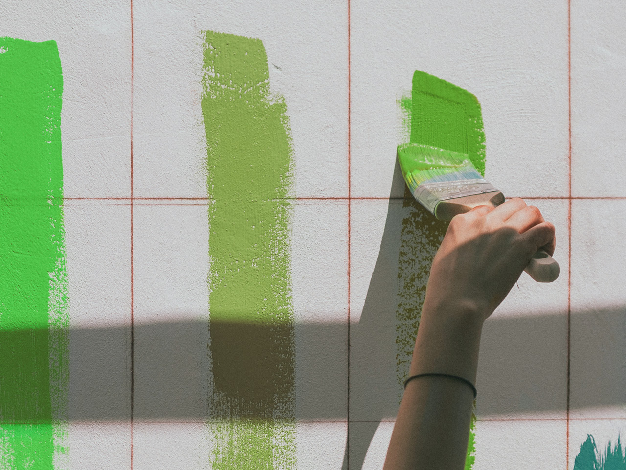 Ein Untergrund wird in verschiedenen grünen Farben angestrichen.