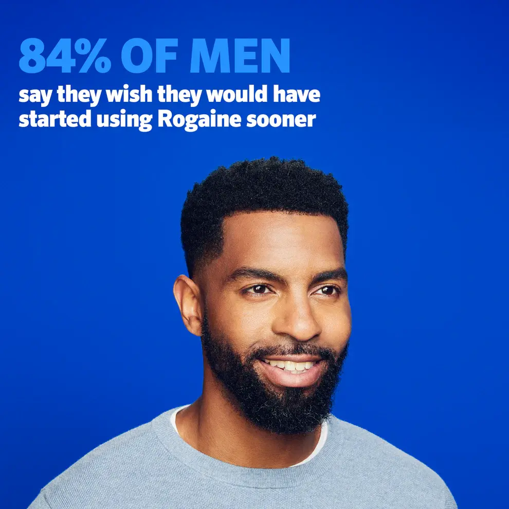 Man with dark brown hair and a beard wearing a blue sweater on a blue background.