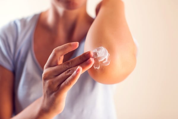  Close up image of a persons upper arm & their hand itching the skin on their arm