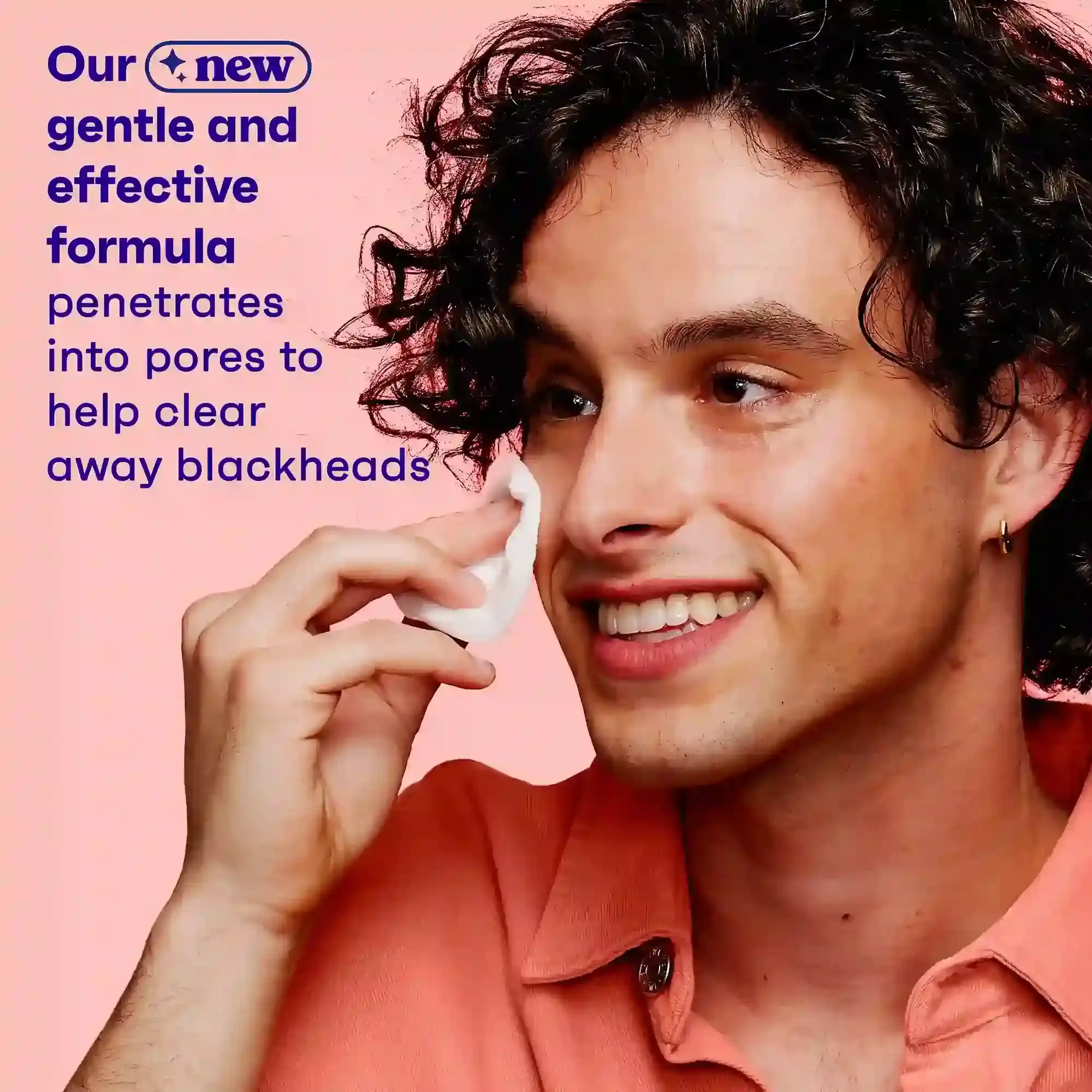 A person smiles while using a cotton pad on their cheek, wearing an orange shirt against a pink background. Text: "Our new gentle and effective formula penetrates into pores to help clear away blackheads."