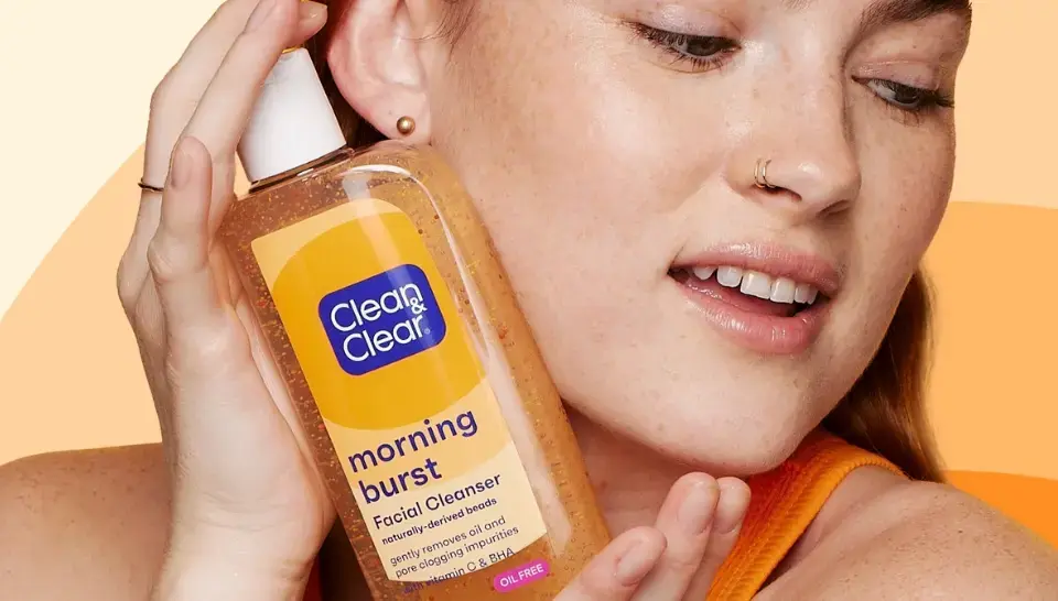 Clean & Clear skincare products featuring Vitamin C enriched Morning Burst Facial Cleanser held by a smiling woman.