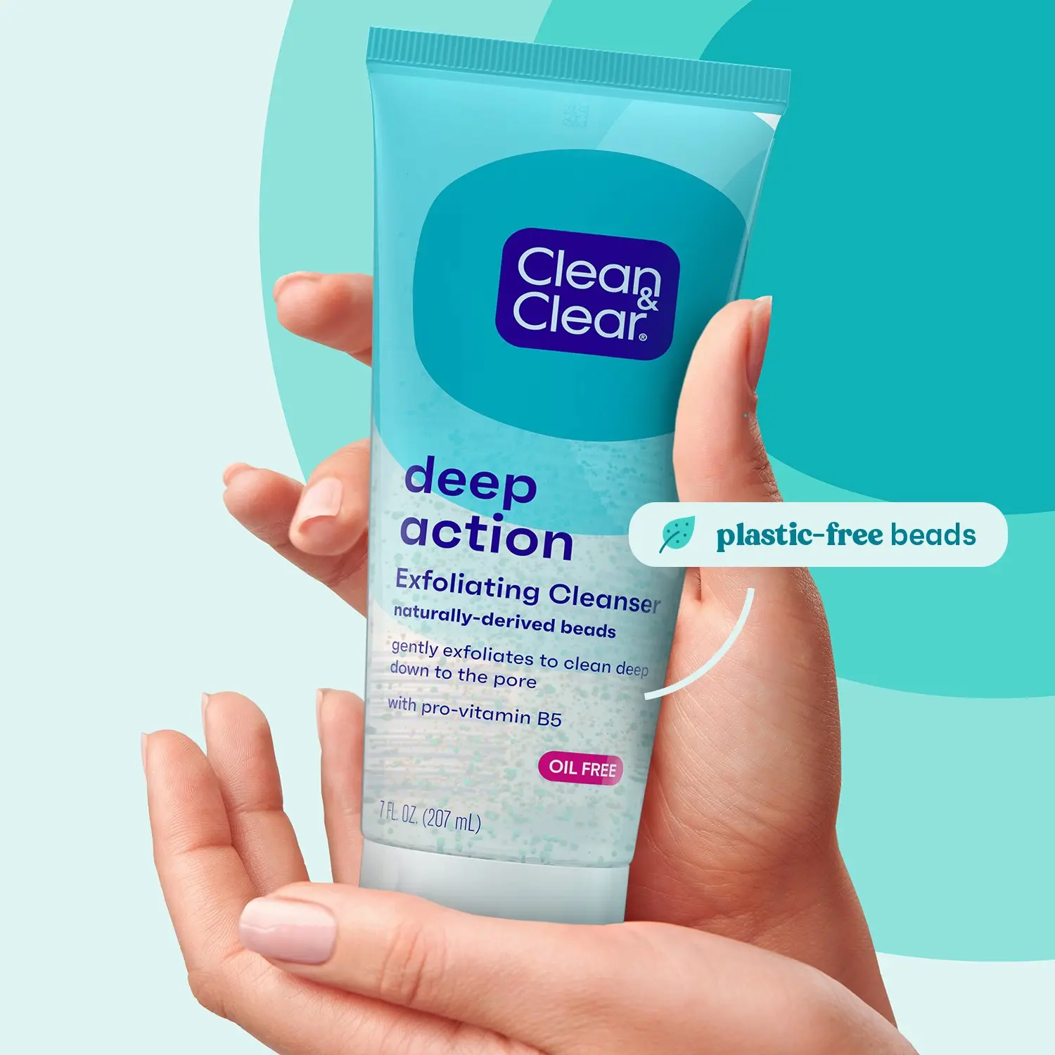 A hand holds a tube of Clean & Clear Deep Action Exfoliating Cleanser. The product features naturally-derived, plastic-free beads and is oil-free with pro-vitamin B5. Capacity: 7 fl oz (207 mL).