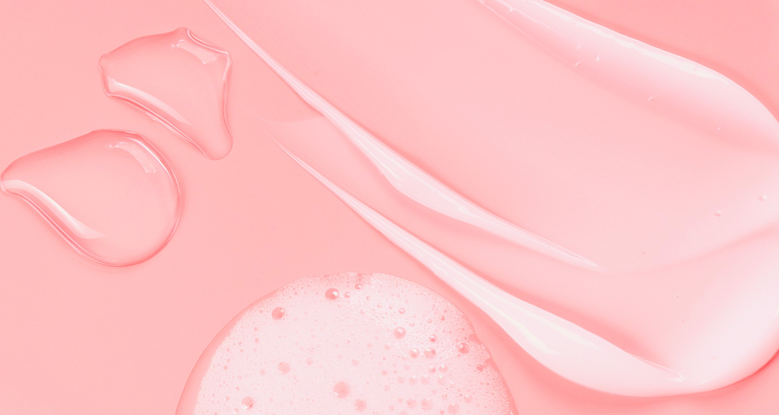 Close-up of skincare cream and gel textures in soft pink hues, illustrating essential skincare products.