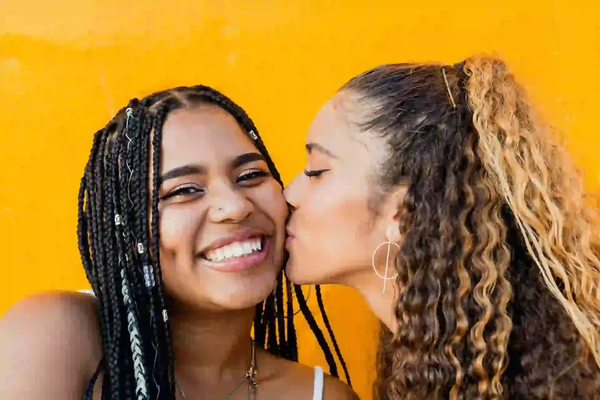 Woman kissing another woman on the cheek