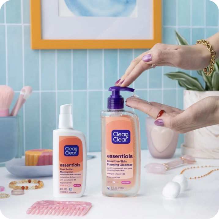Woman applying Clean & Clear® Essentials Foaming Cleanser and Essentials Dual Action Moisturizer in a well lit bathroom