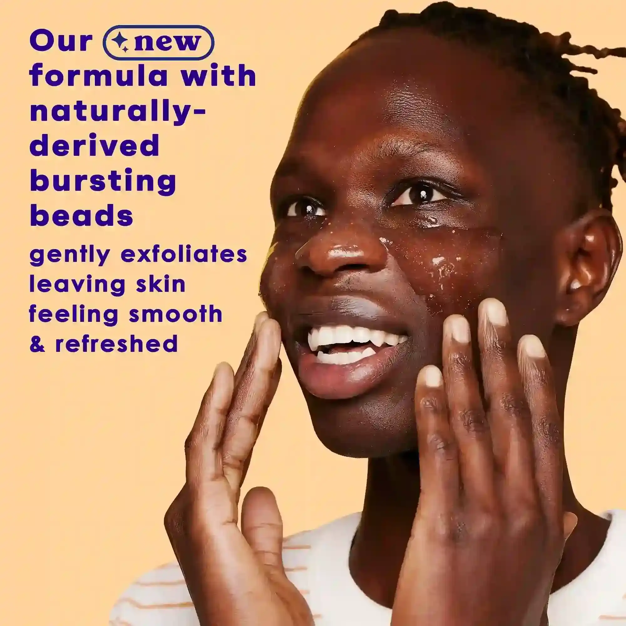 A person applies exfoliating gel with bursting beads to their face, smiling against a peach background. Text reads: "Our new formula with naturally-derived bursting beads gently exfoliates leaving skin feeling smooth & refreshed."