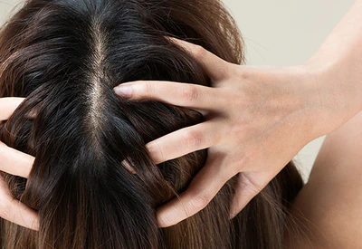 A woman with long brown hair massaging her scalp with her fingers