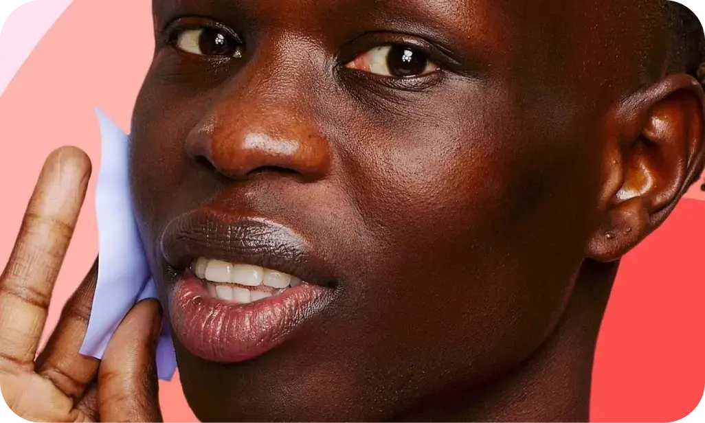 A person holds a blue object against their cheek, set against a background of pink and red gradient shapes.