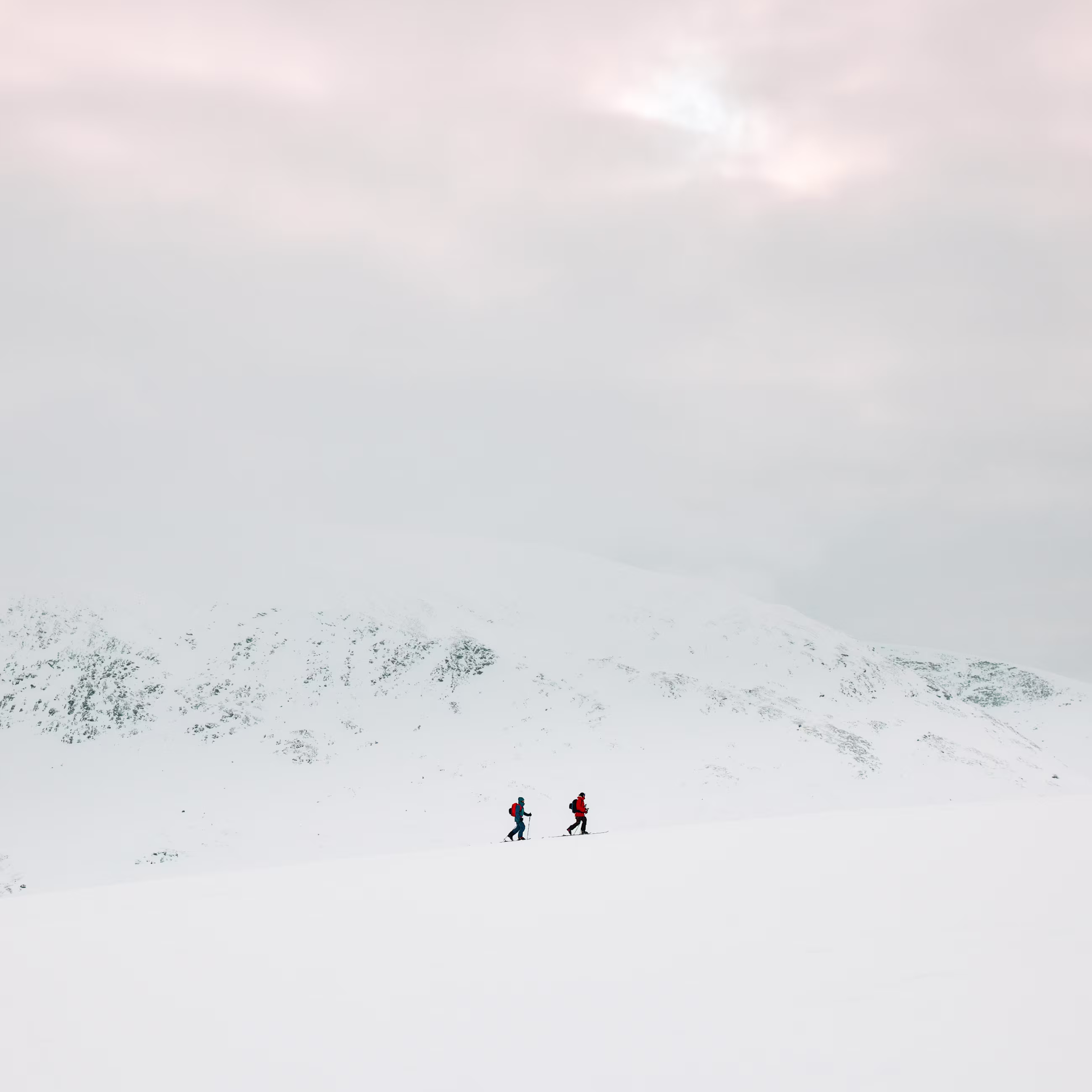 2 guys ski touring in a snowy weater in the mountains