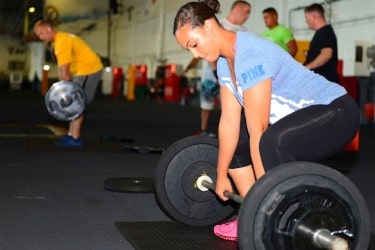 A photo of a woman going down to deadlift a barbell with weight 